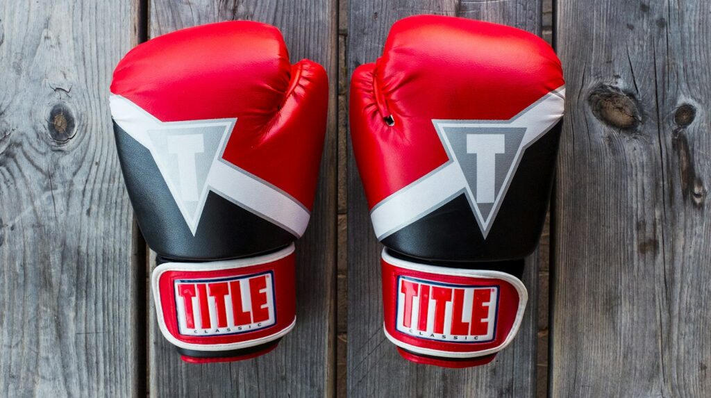 pair of red-and-black Title training gloves Mike Tysongrey wooden plank